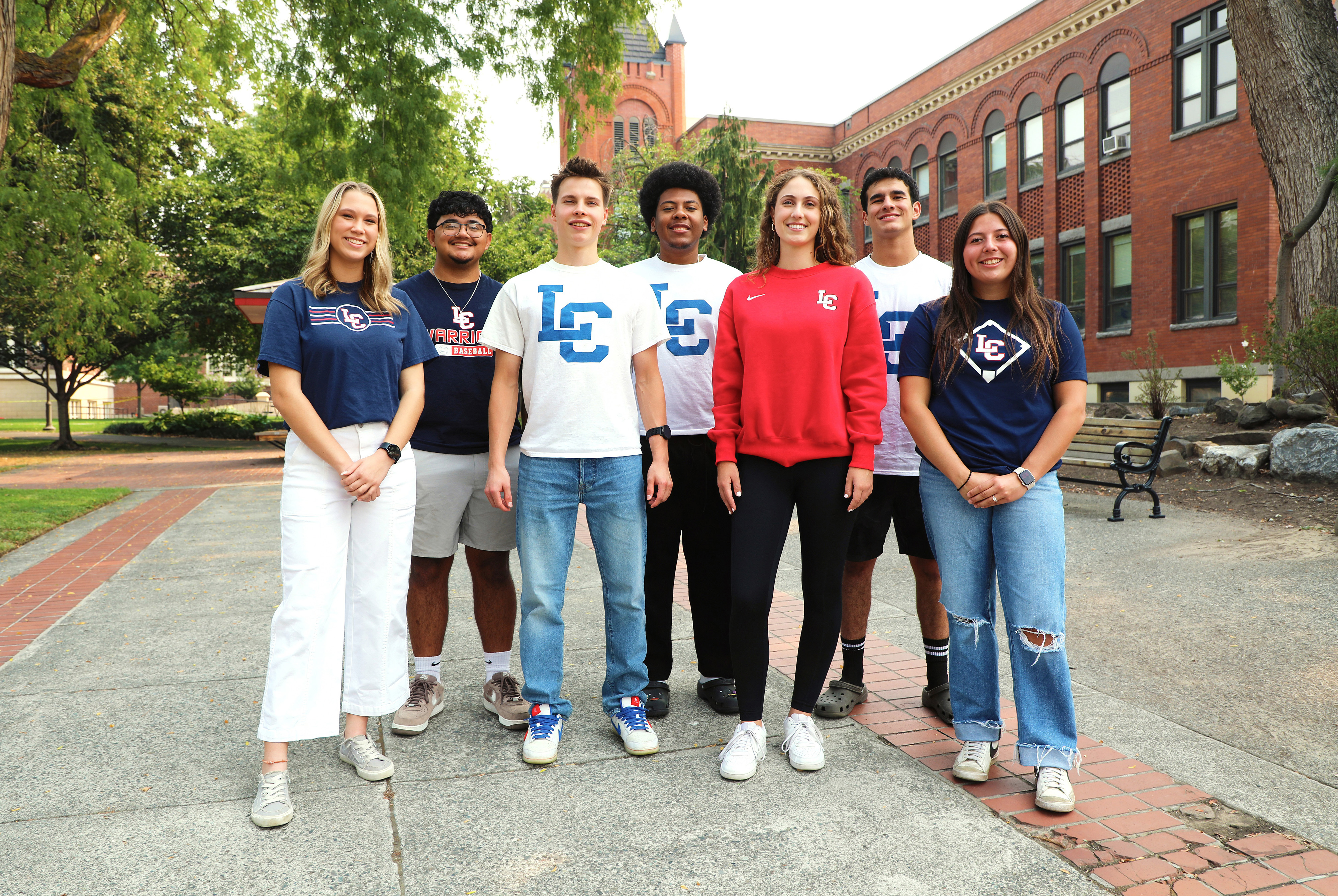Seven students stand posed in front of clock tower