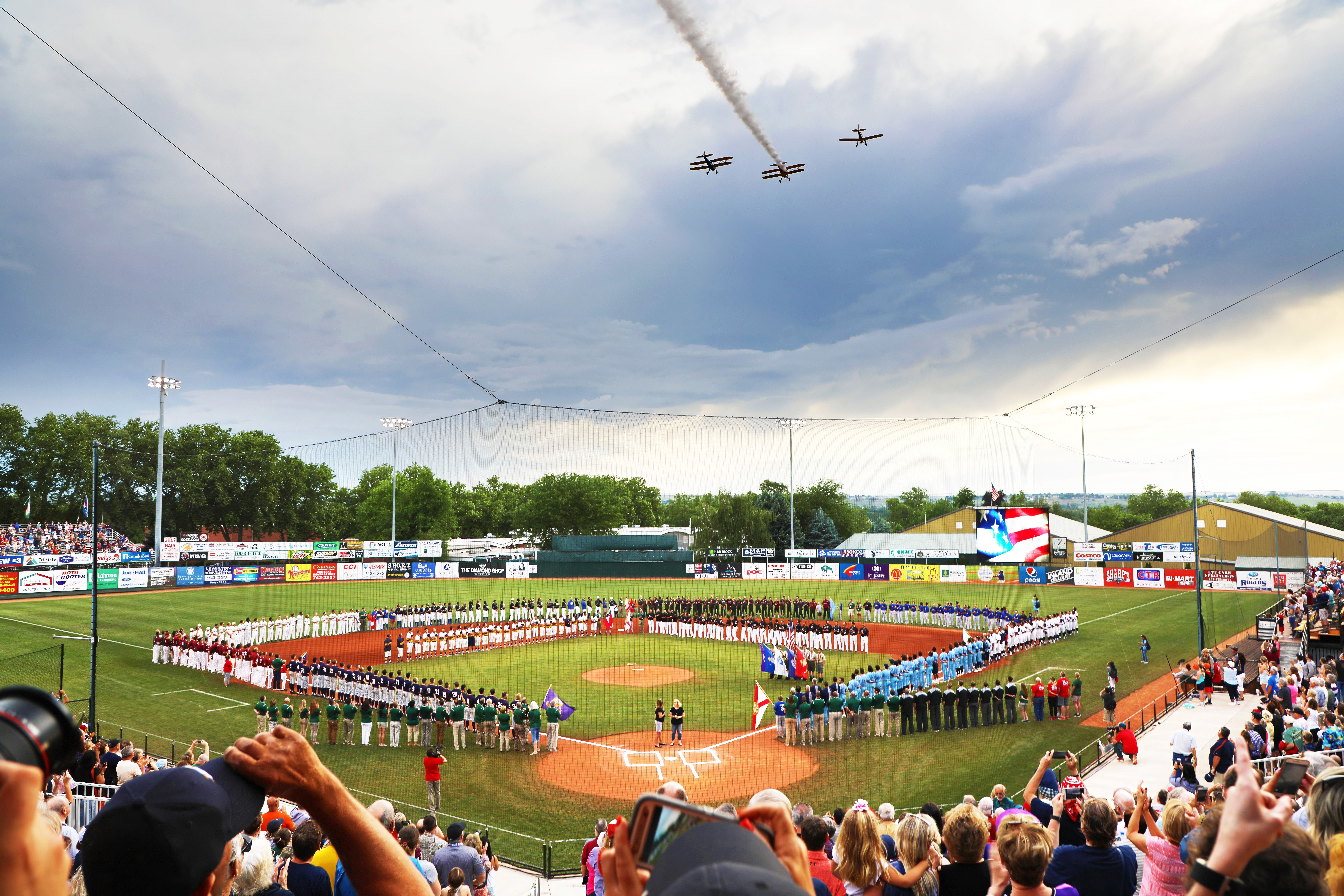 Multiple teams line LC State's Harris (Baseball) Field while three planes fly above field and crowd watches from stands