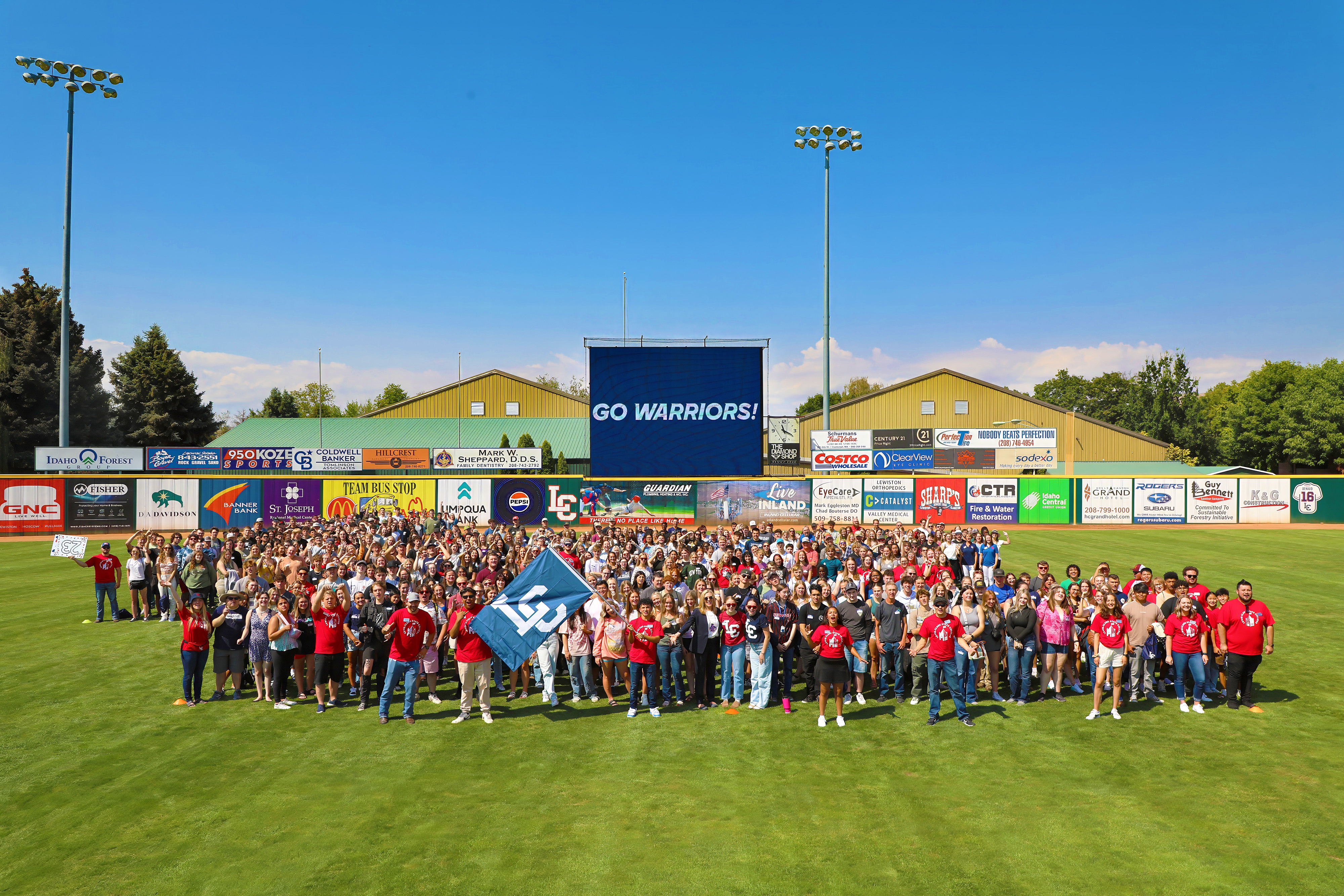 LC State students gathered on baseball field for group picture with score board that reads "GO WARRIORS!"