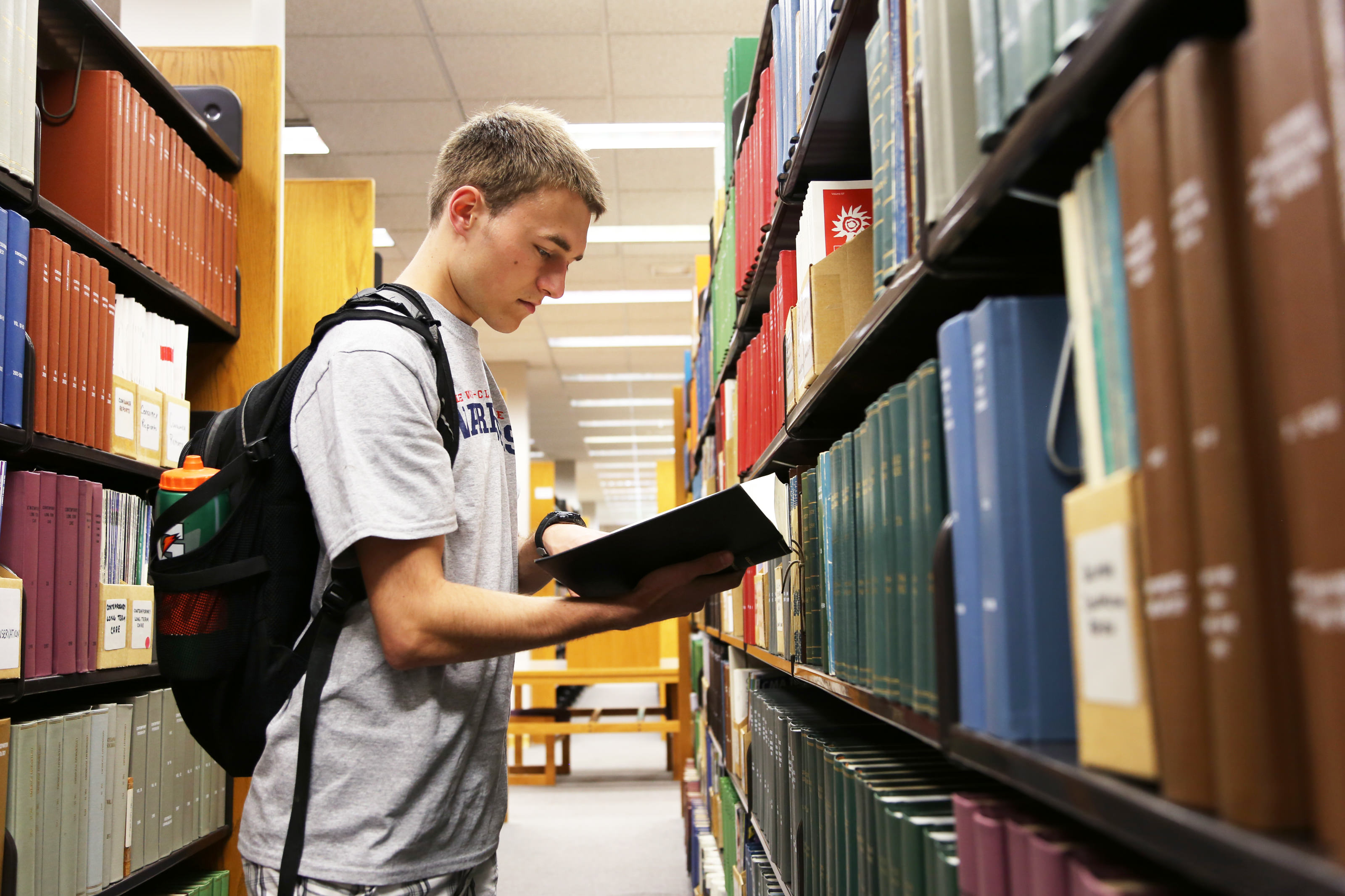 Male student looking at book in library