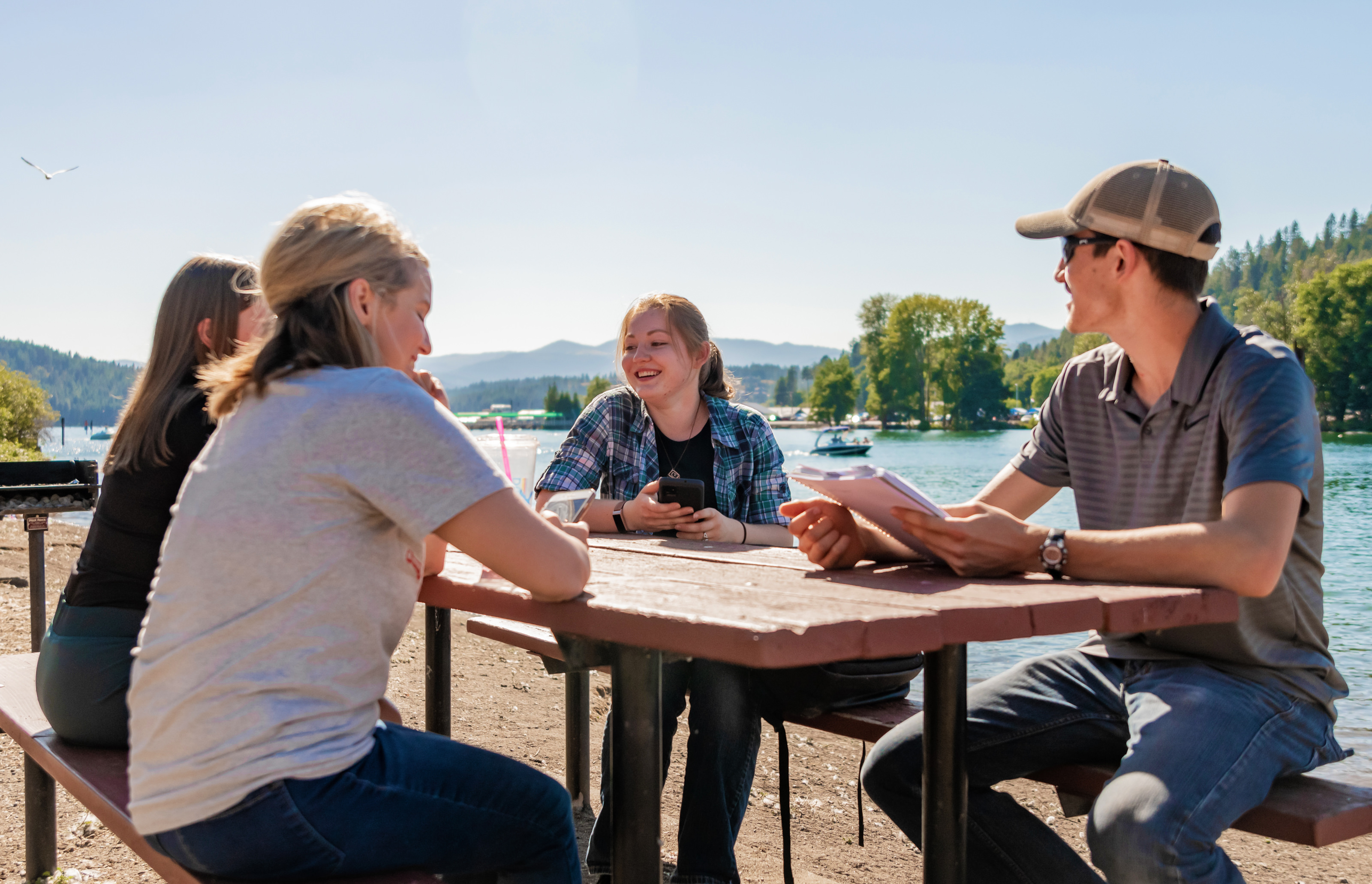 Students sitting outside at a picnic table by lake