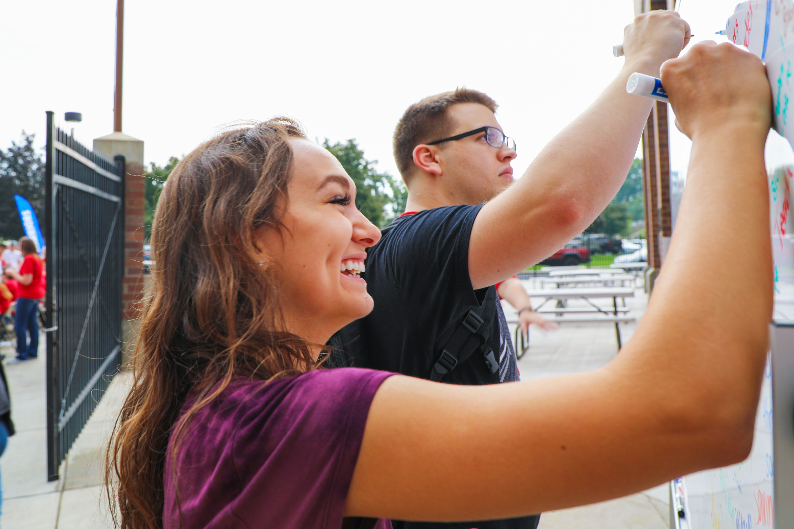 Female student writing on a white board outside