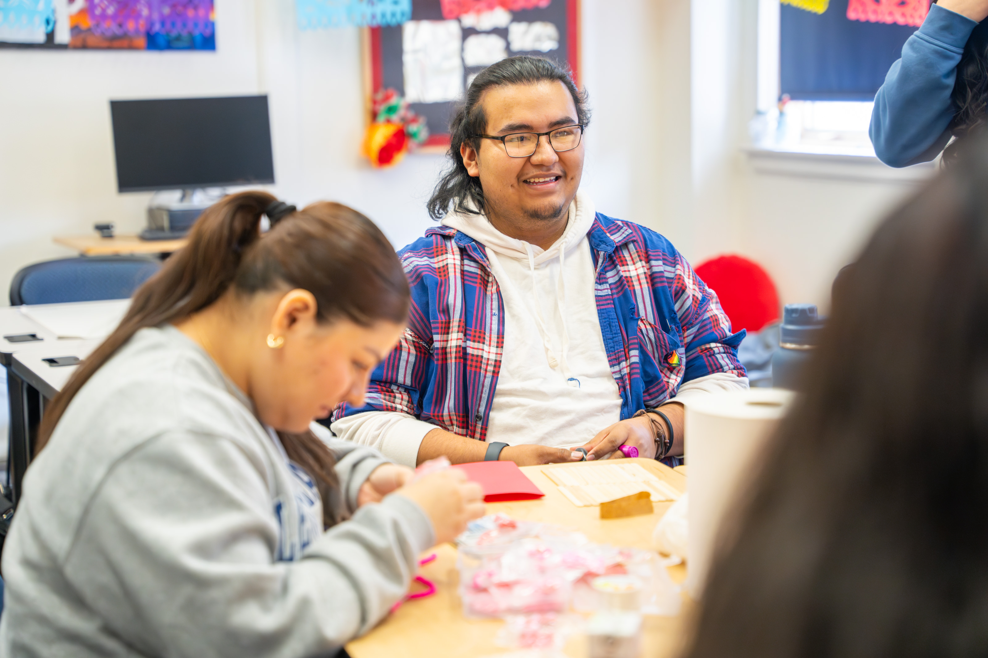 Students sitting down at a table working on crafts