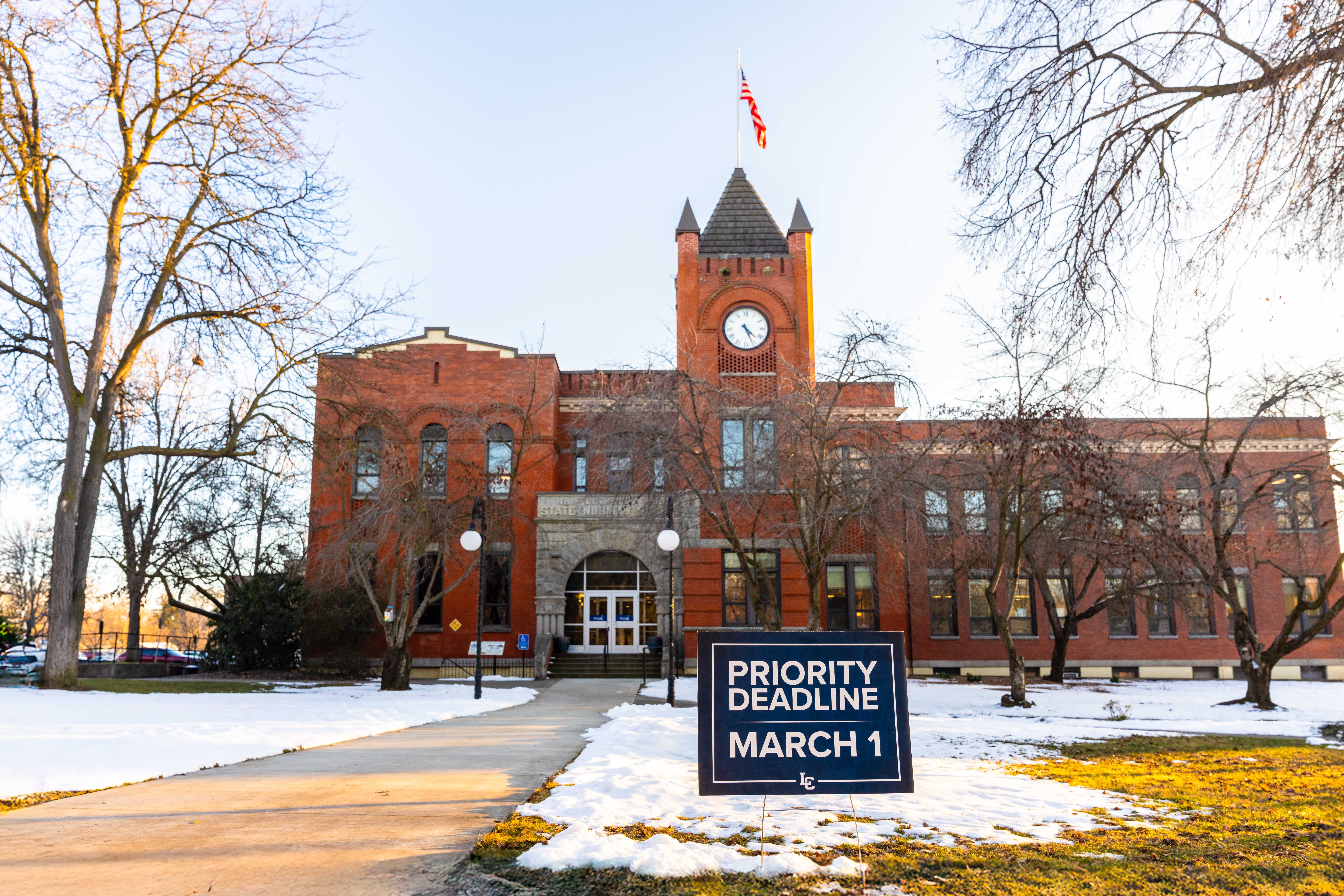 Sign reading "Priority Deadline March 1" with LC Symbol outside of LC State's Reid Centennial Hall Clock Tower