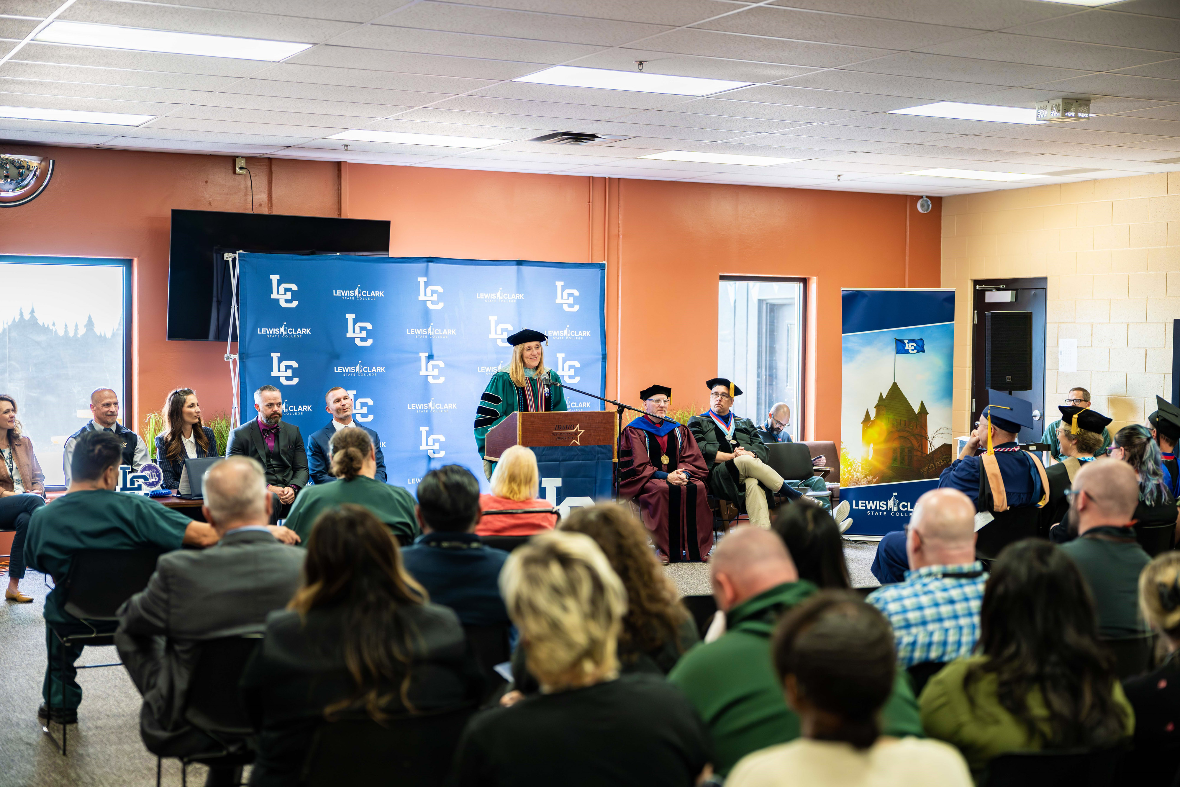 President Pemberton speaks behind podium with people sitting in audience listening for the ISCC commencement. 