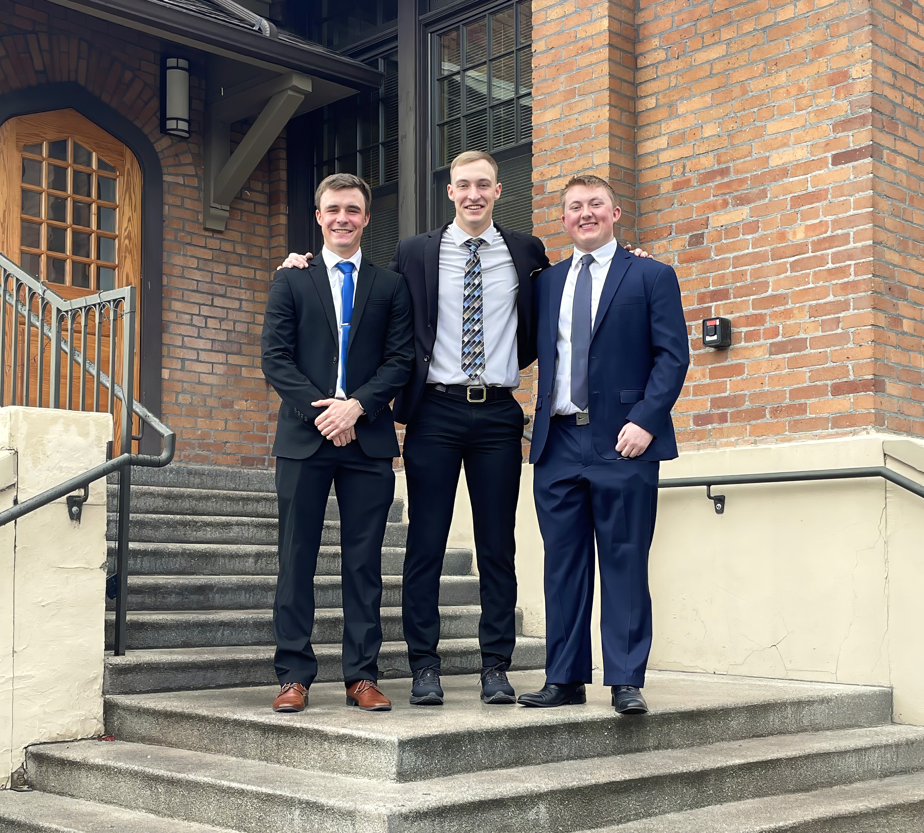 Three students posed in front of Thomas Jefferson Hall Doorway wearing business attire