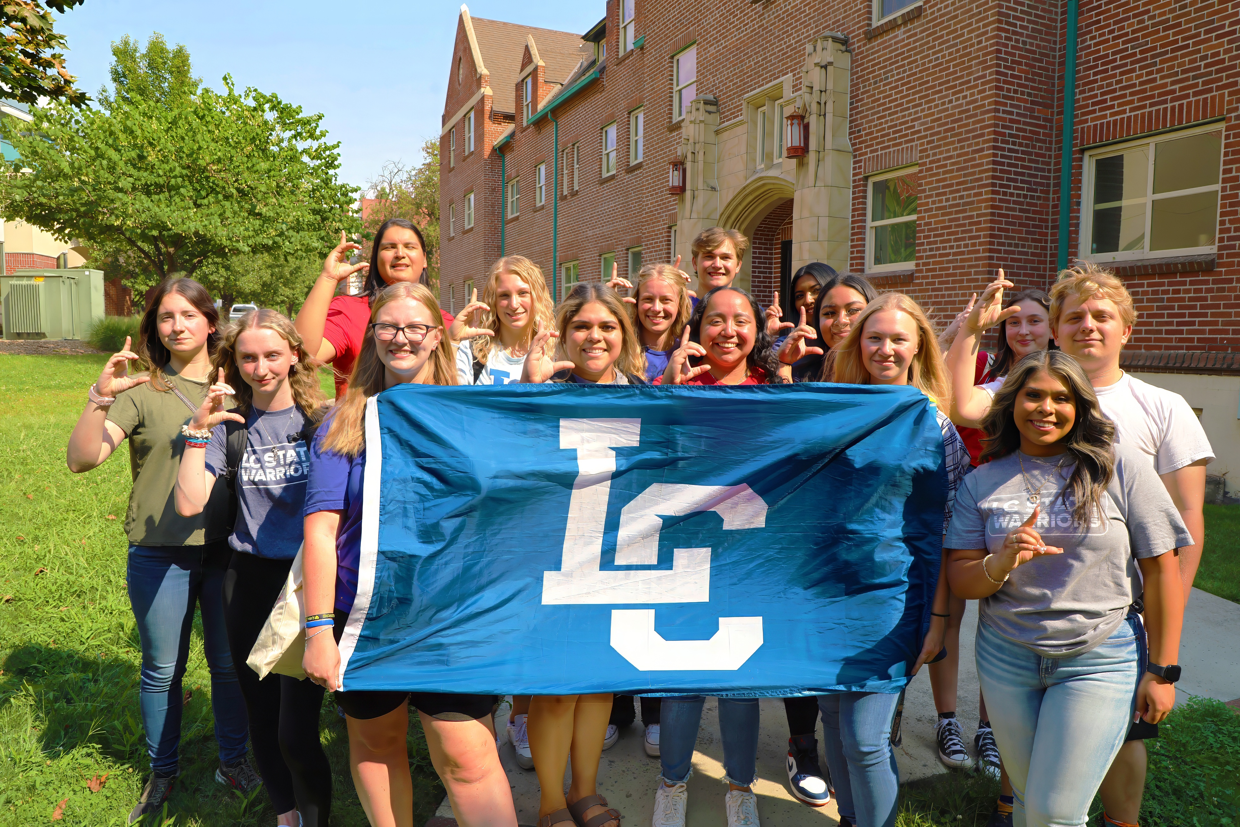 Students holding LC State flag in front of Talkington Hall