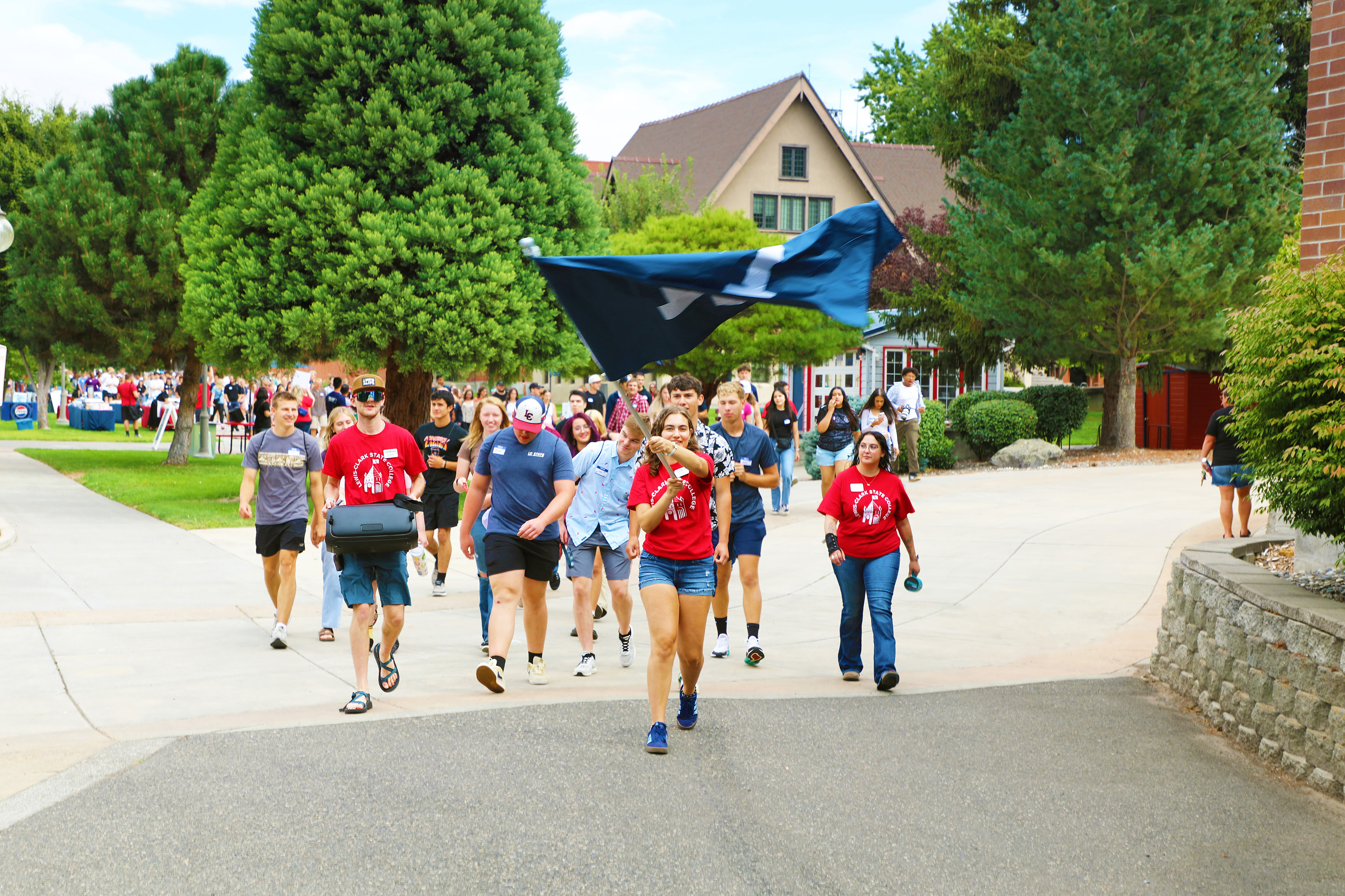 LC State students walk on campus waving the school flag