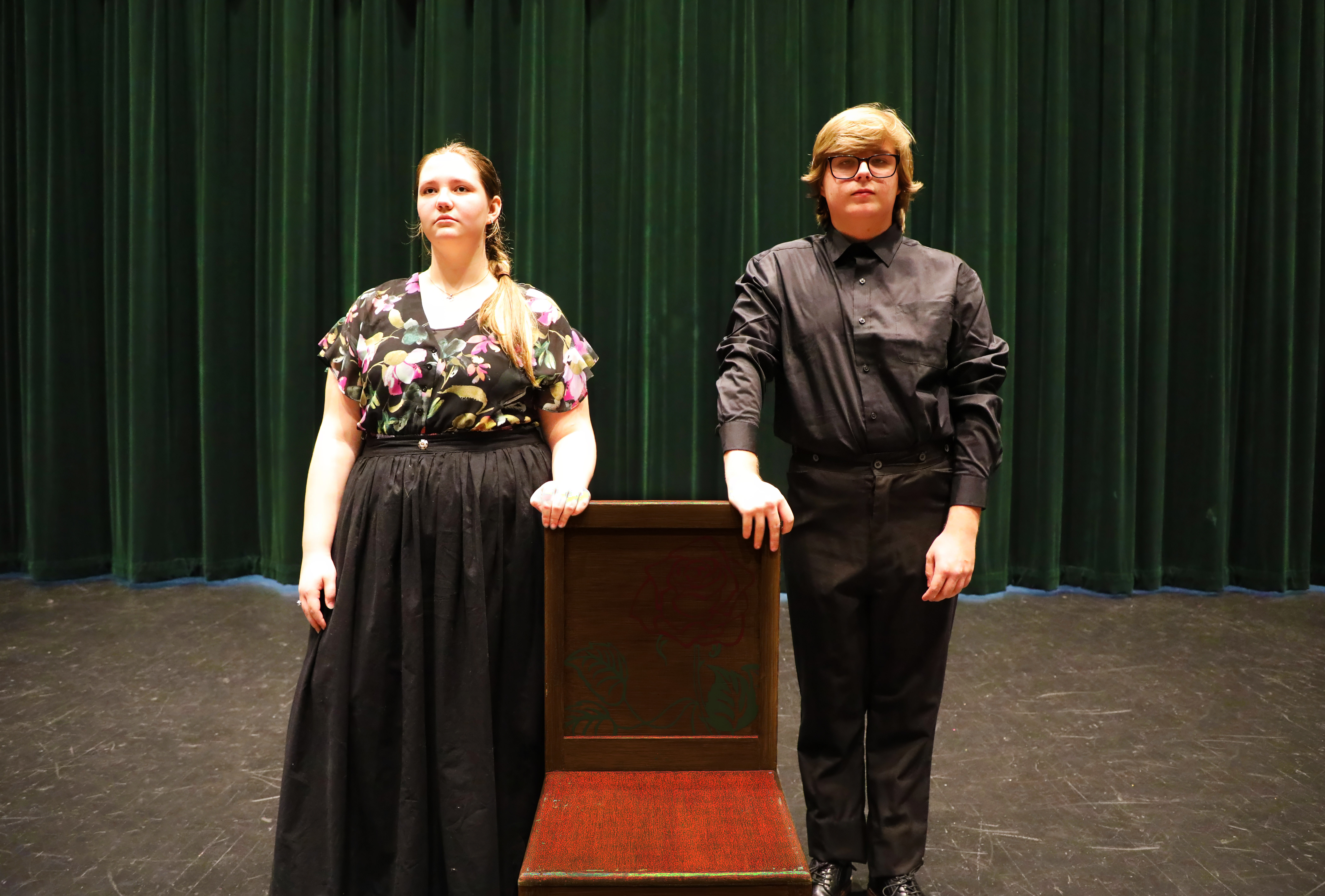 Actors Jessica Riggs and Zachary Steadman pose on stage with chair