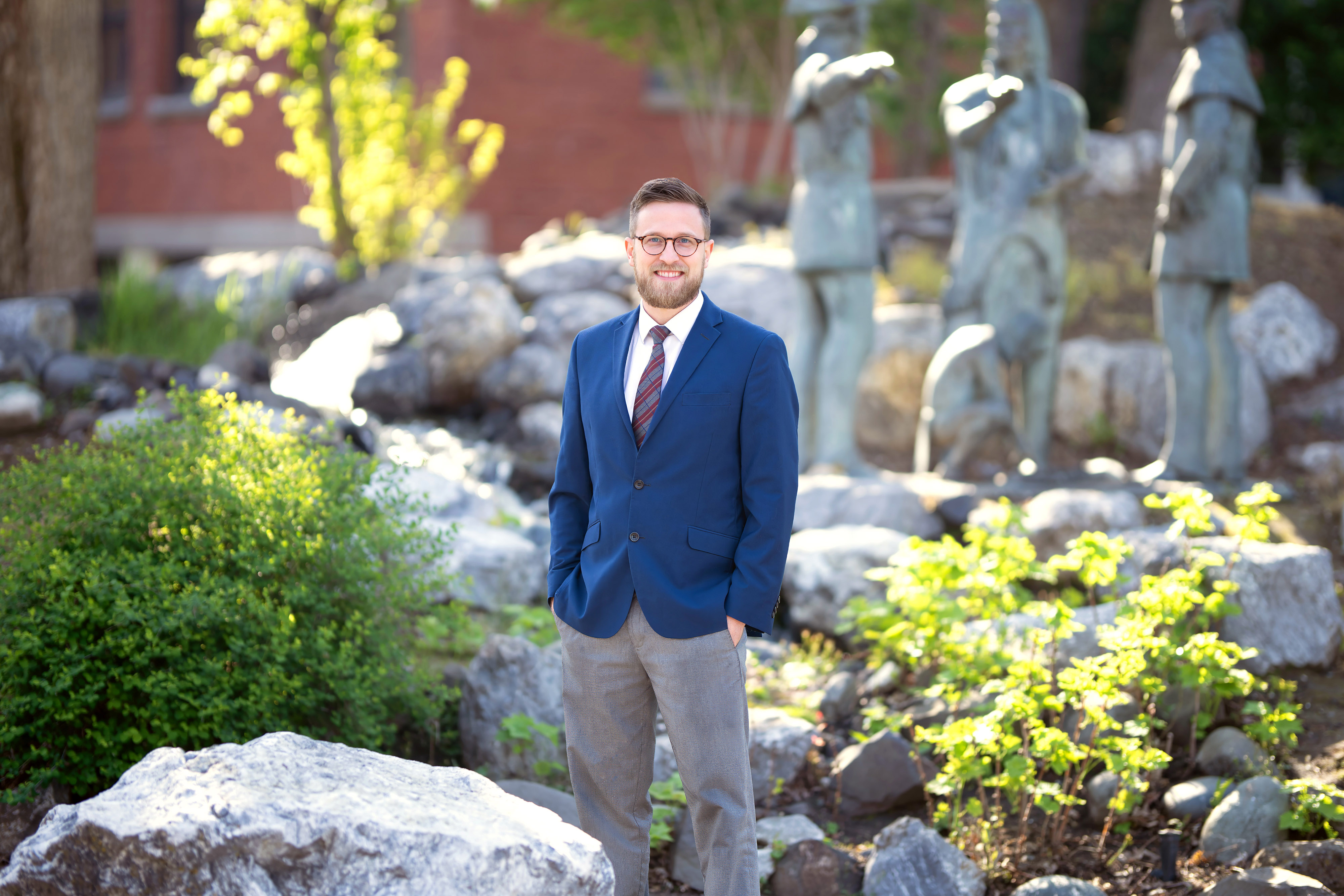 Photo of Logan Fowler standing in front of LC State's fountain with statues